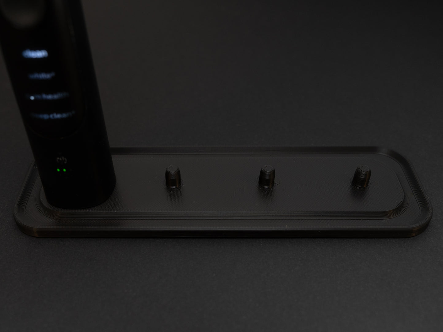 Philips Sonicare electric toothbrush stand that holds four toothbrushes shown in black.