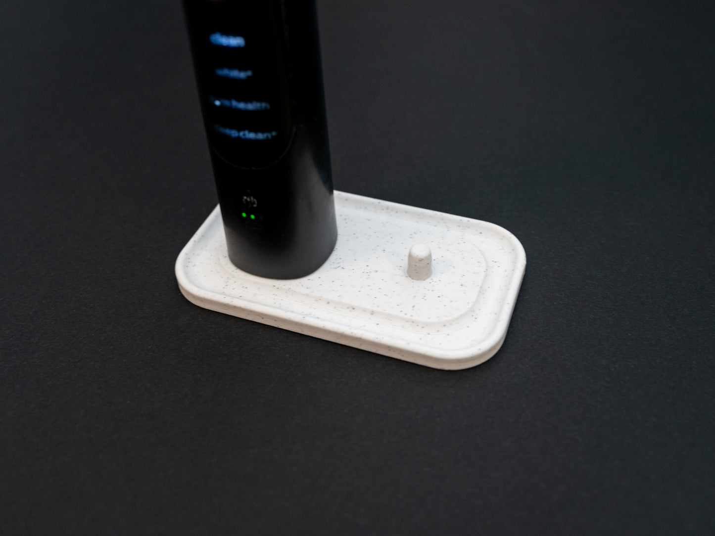 Philips Sonicare electric toothbrush stand that holds two toothbrushes shown in white stone effect.