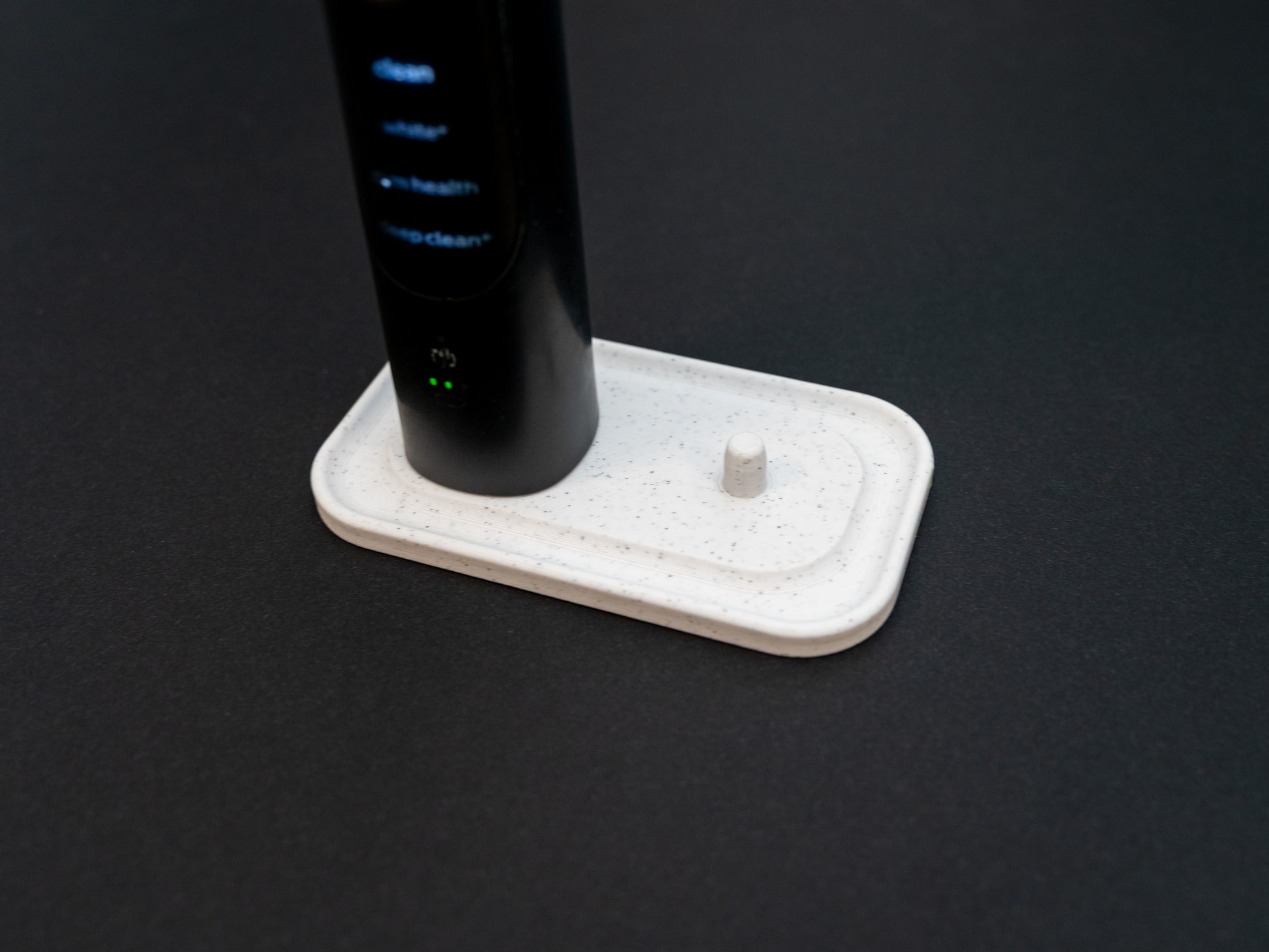 Philips Sonicare electric toothbrush stand that holds two toothbrushes shown in white stone effect.