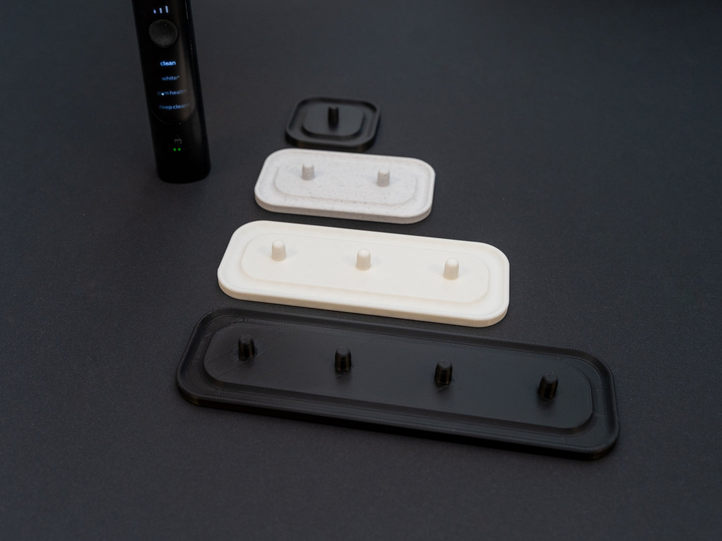 Philips Sonicare electric toothbrush stands that hold one, two, three or four toothbrushes shown in white stone effect, black and white.