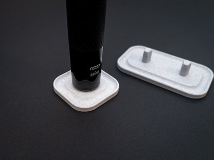 3D printed Oral B toothbrush stand in white marble stone colour on a black background. Picture shows a stand for one toothbrush and one for two toothbrushes. Stops toothbrush from falling over and organises the bathroom