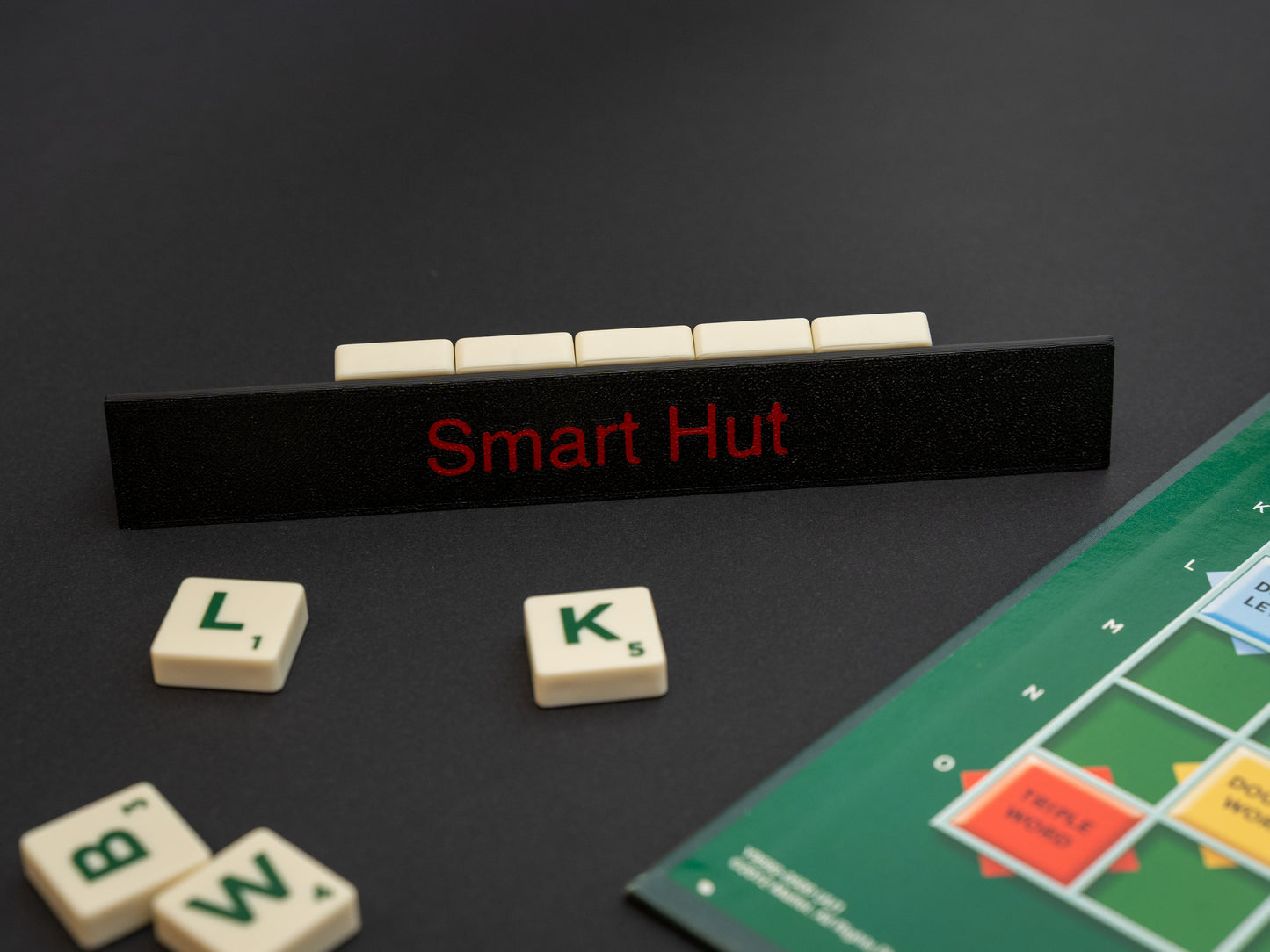 Personalised black scrabble and bananagrams tile holder. Shown with the personalisation in red text at the front and tiles in the tray at the back.